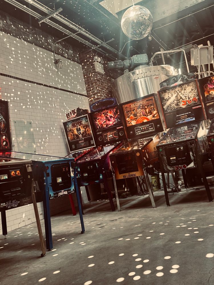 Two banks of pinball machines with a mirrorball reflecting the afternoon sun. 