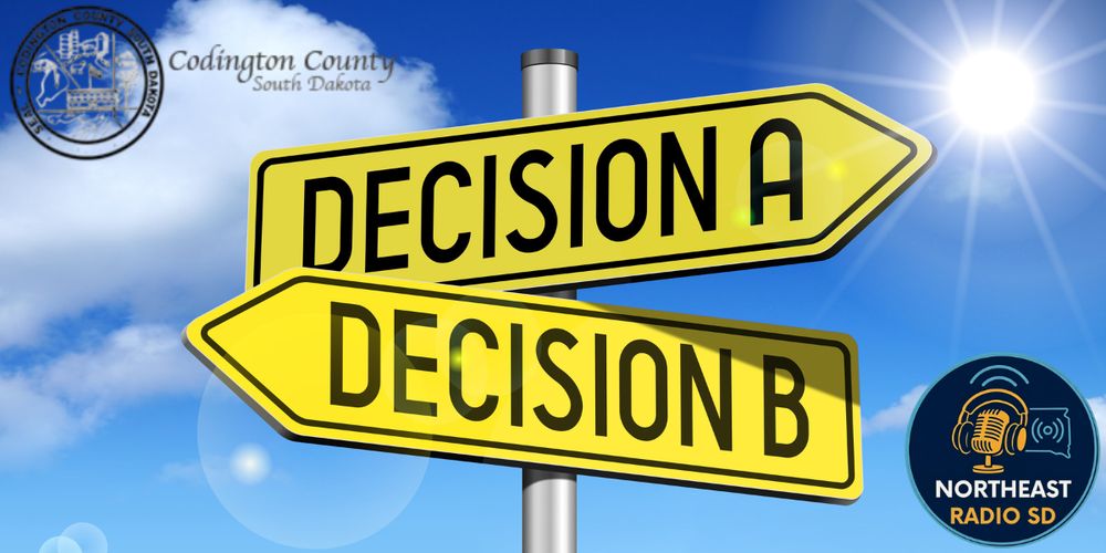 Yellow signpost with "Decision A" and "Decision B" against blue sky. Seals of Codington County, SD, and Northeast Radio SD logo visible.
