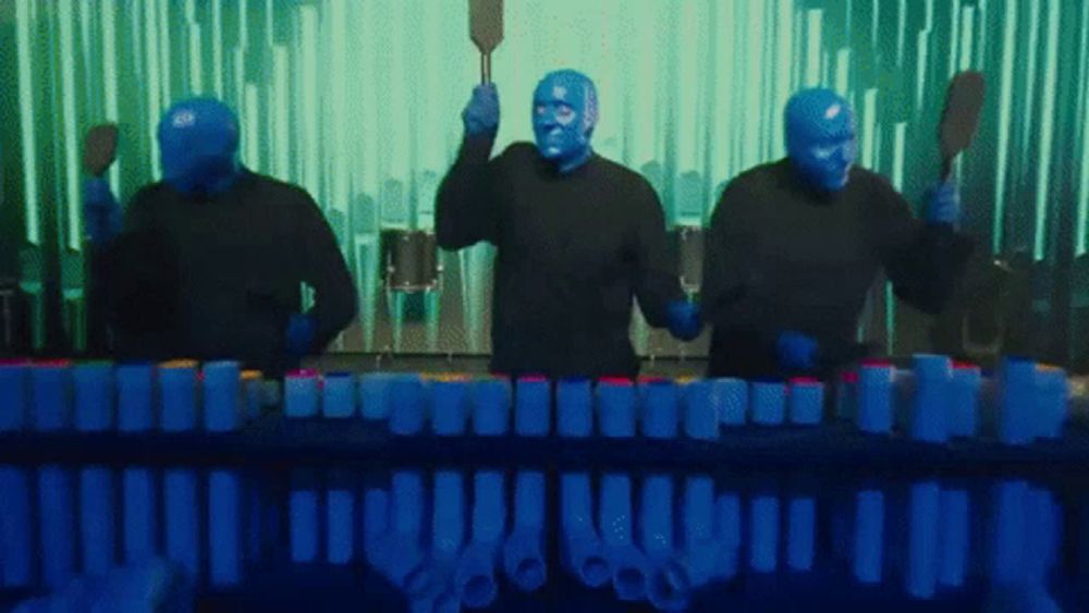 a group of men with blue faces are playing a musical instrument