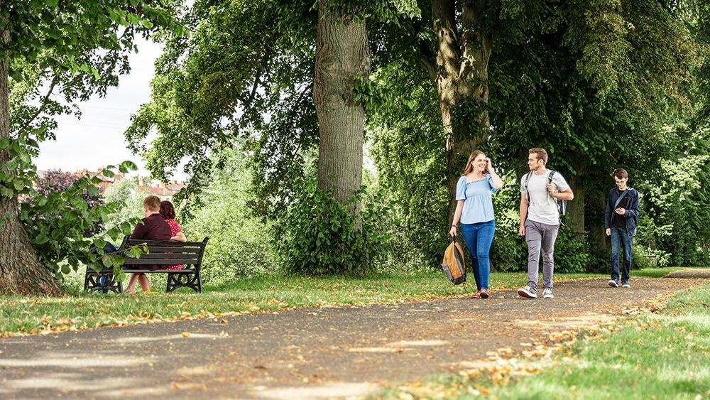 Two students walking through a park beside the river