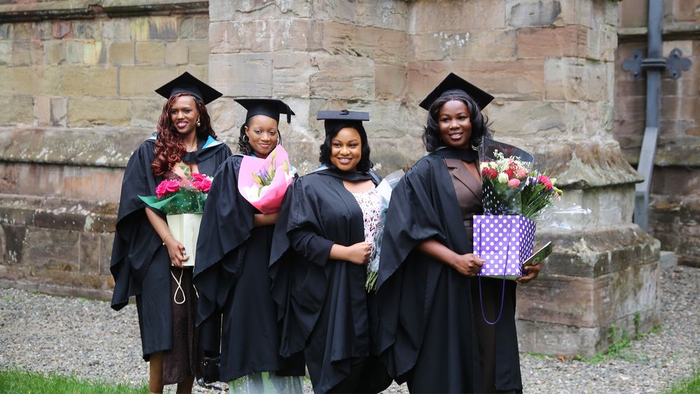 Group of graduates stood outside the cathedral holding bouquets of flowers