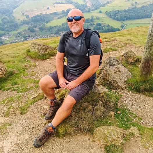Andy sat on a hill side in walking gear