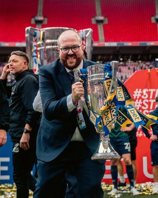 Craig smiling as he holds a trophy