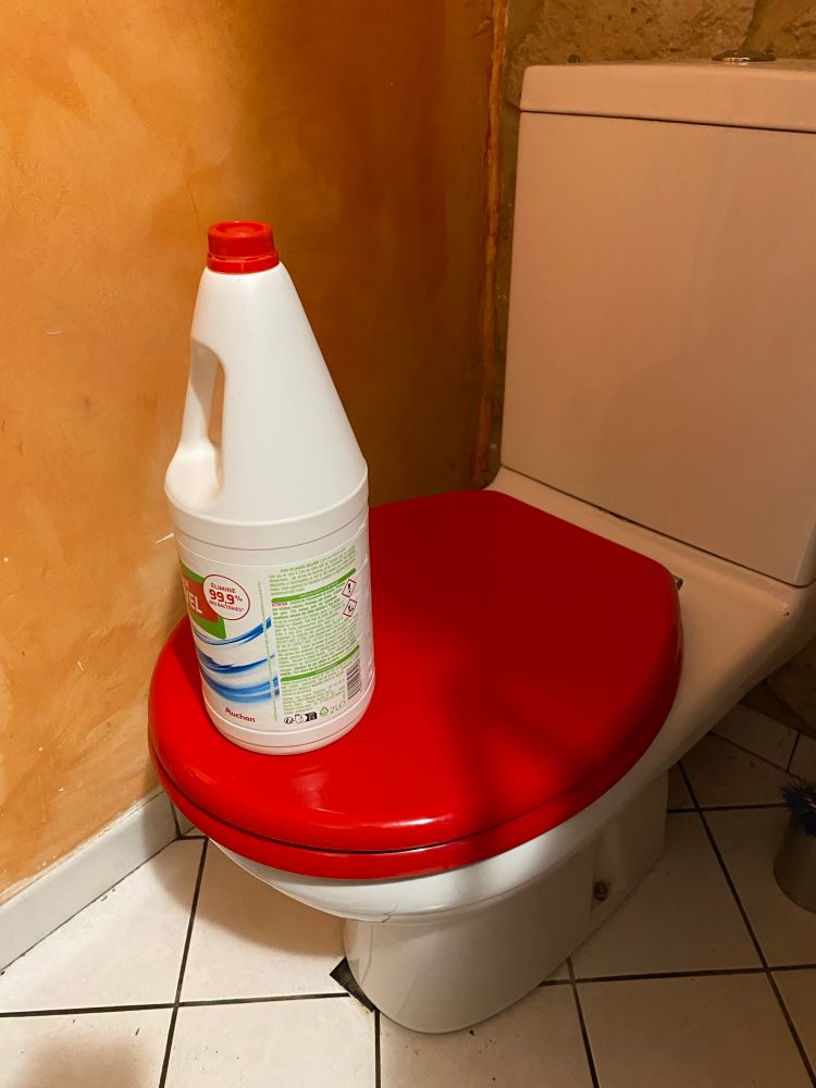 Une bouteille d’eau de Javel pleine maintient un abattant de toilettes en position fermée.