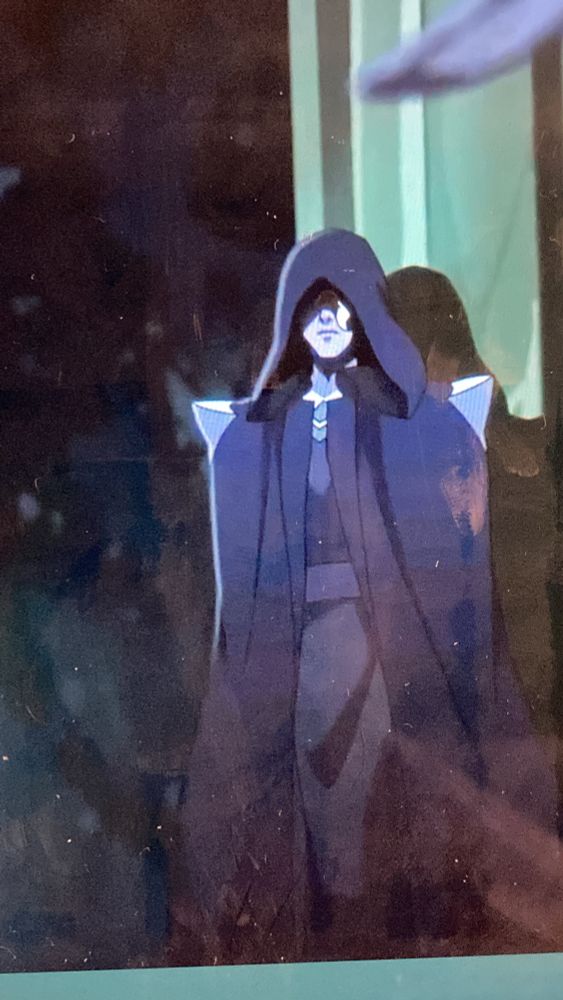 An animated still of mysterious, robed figure who is definitely a) hot and b) a boi, their face shrouded and a lock of white hair visible 
