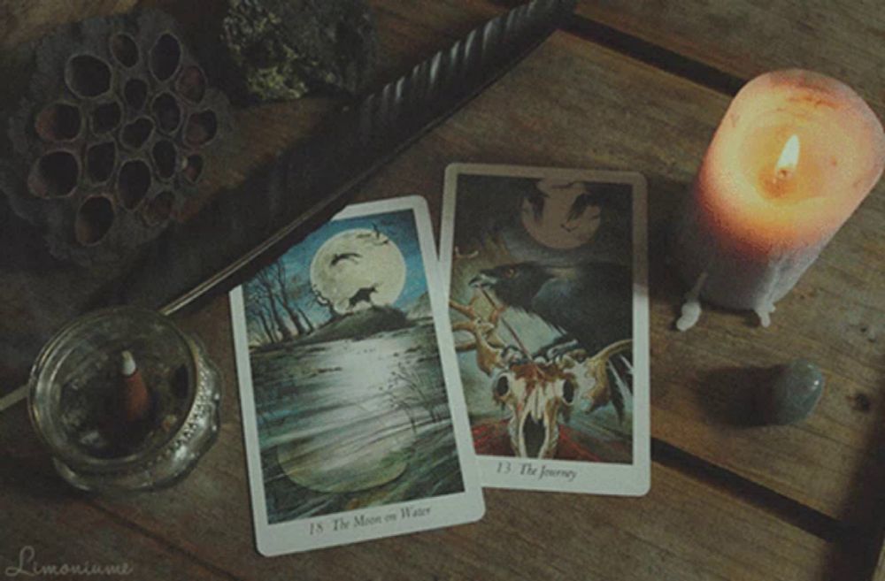 two tarot cards on a table with the moon on water and the journey