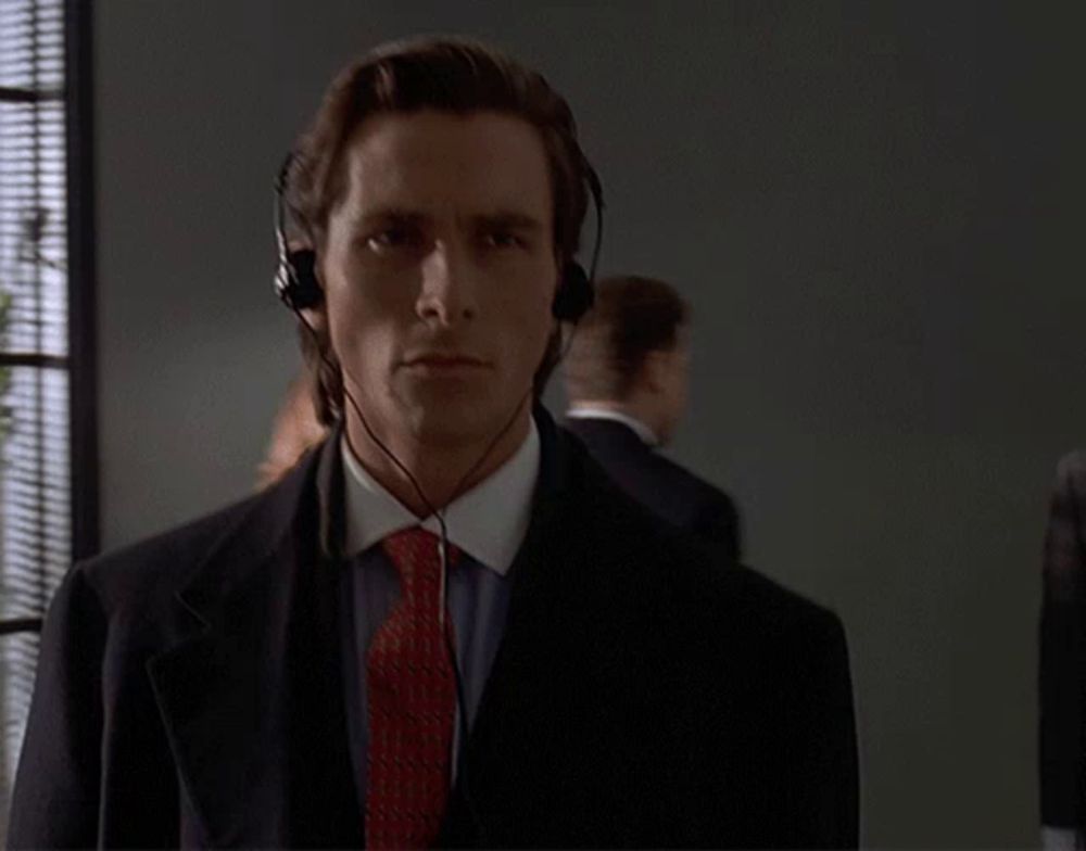 a man wearing headphones and a red tie looks at the camera