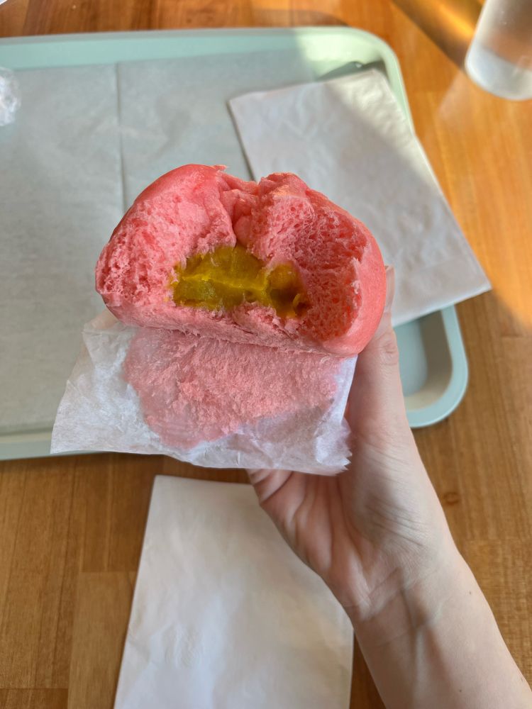 A partially eaten red bao with pumpkin filling.