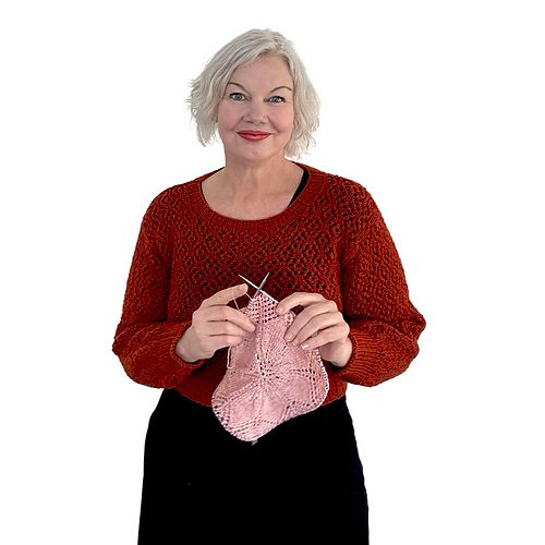 Ambah knitting a lace square looking at the camera 