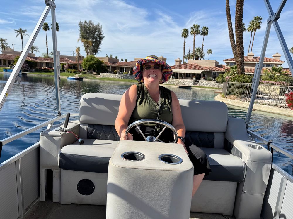 Smiling woman steering a boat on a manmade lake