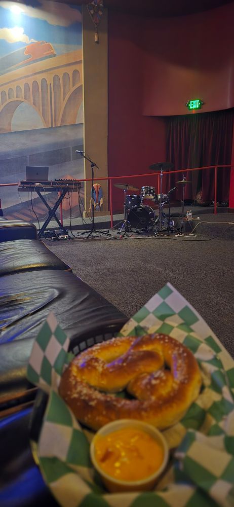 Screenland Armour, Theater 1 - drums and synth set up for a live score of Faust. A soft pretzel with cheese is in the foreground.