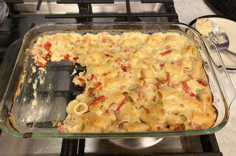 A big baking dish of macaroni and cheese with rigatoni noodles. It has some blue cheese and parmesan in there, plus cream cheese for creaminess, so it smells sharp and aromatic and cheese and bubbly and golden.