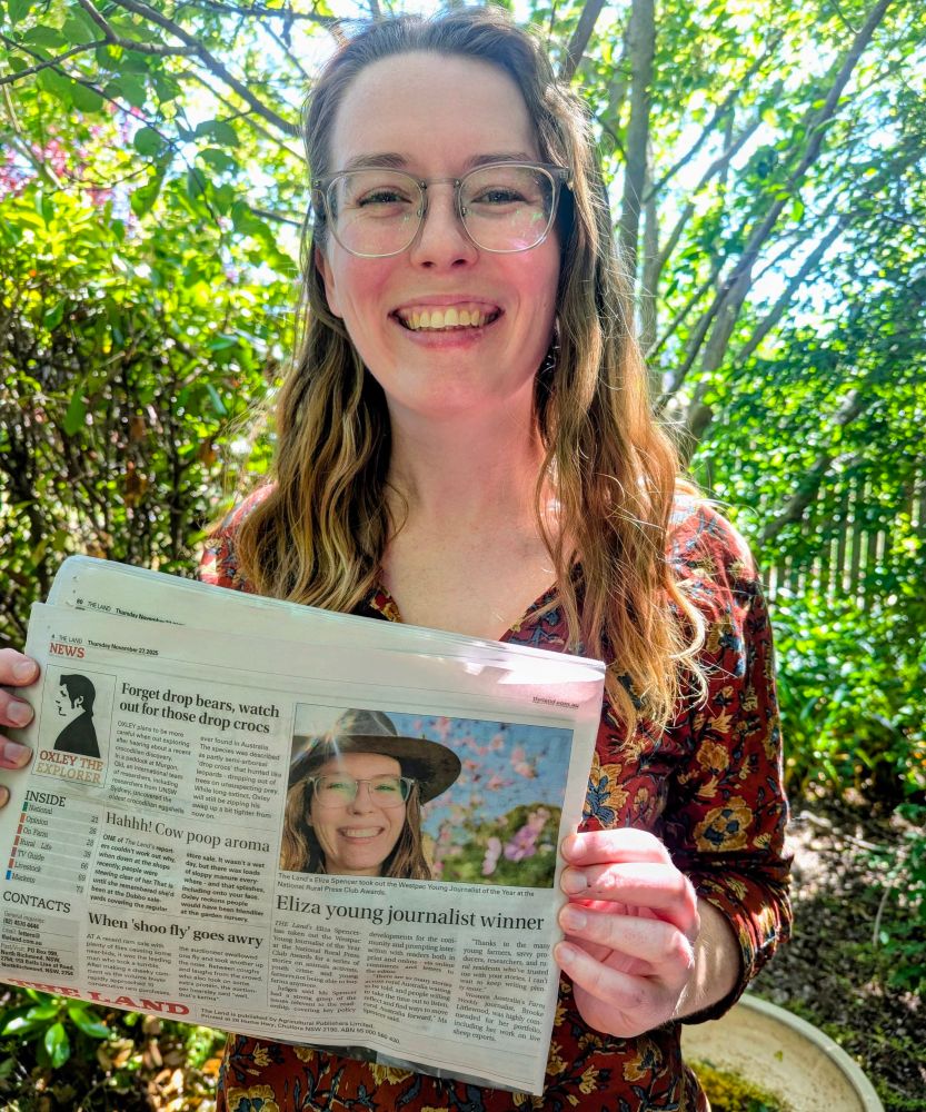 Eliza is holding a copy of The Land newspaper which reads "Eliza young Journalist winner"