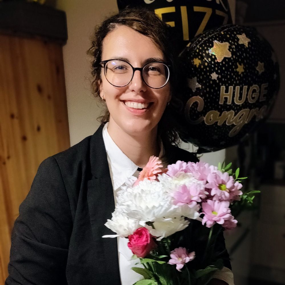 photo of me holding flowers with congratulations balloons behind.