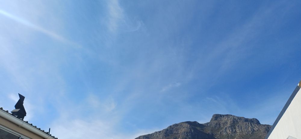 The rocky top of Devil's Peak under the blue sky above Cape Town.