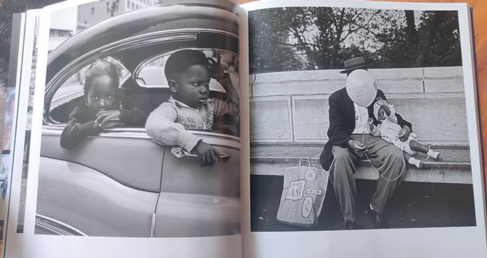 New York 1955, 2 enfants à la fenêtre d'une voiture, un homme assis sur un banc qui sert son bébé dans ses bras, le visage caché par un ballon de baudruche