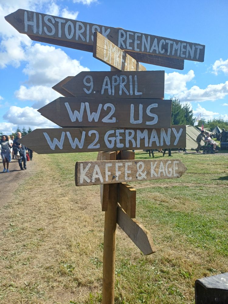 Wooden signpost with arrows pointing towards, 9. April, WW2 US, WW2 Germany, and coffee & cake.