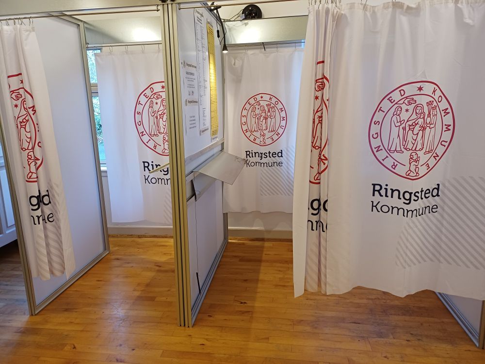 Two empty voting booths with drawn curtains.