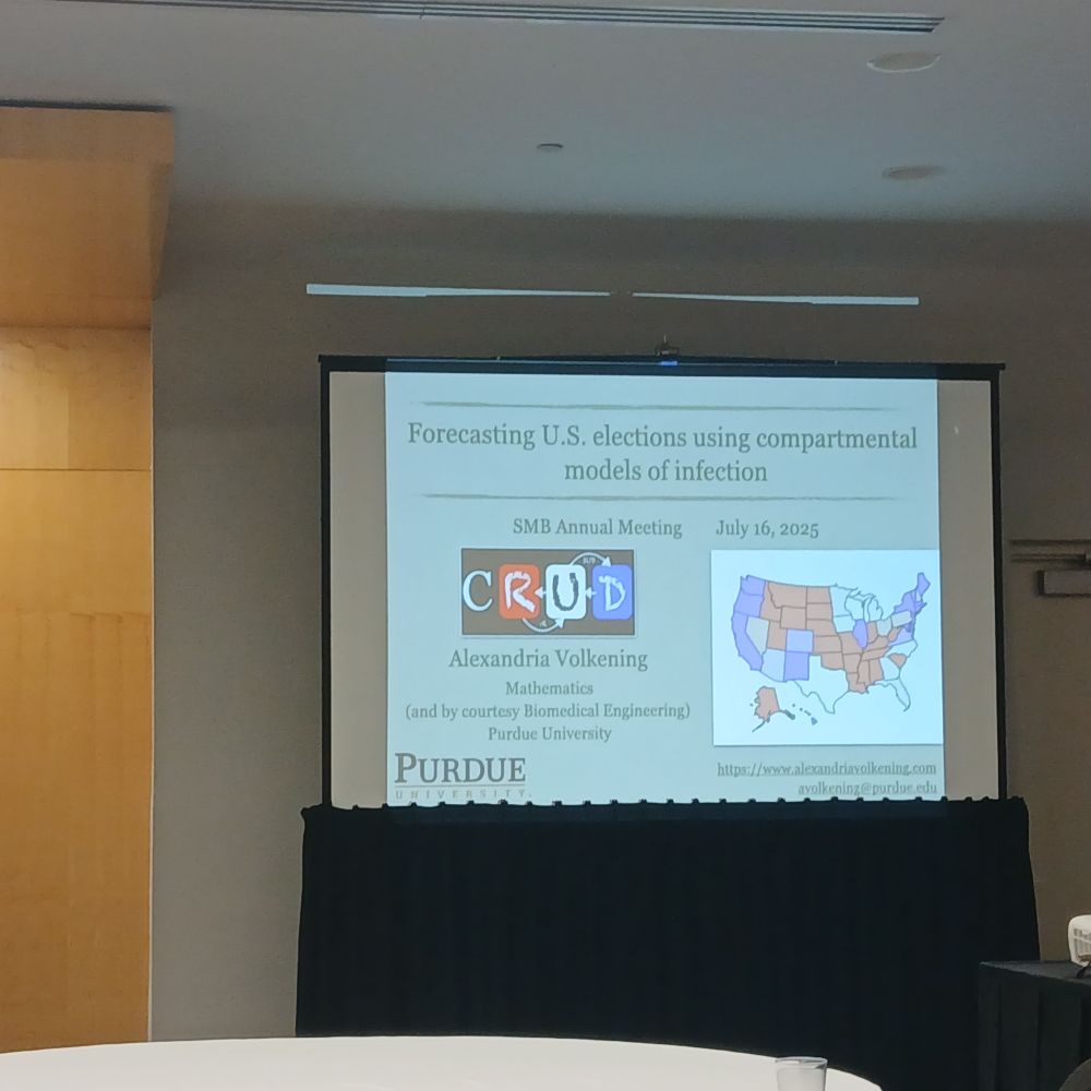 Photo of the intro slide of the talk, featuring a schematic of the compartmental model and a sample image of a projected US presidential election prediction map.