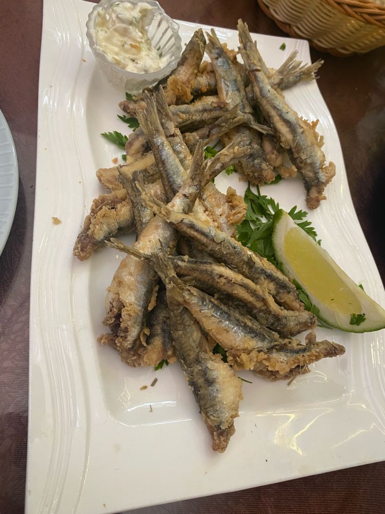 Fried anchovies plated with lime wedge and sauce