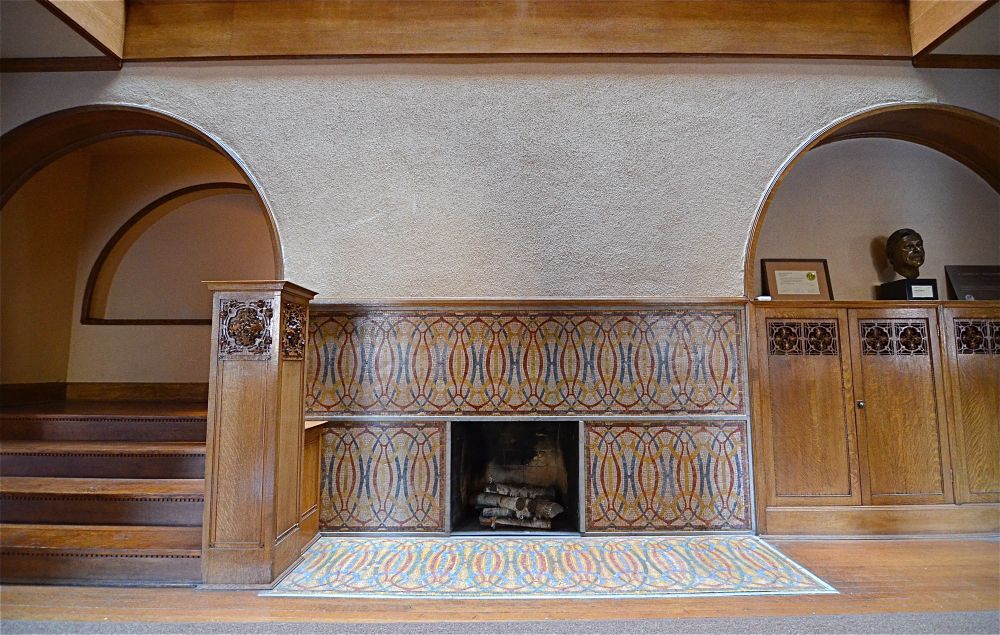 My photo of the James Charnley House (1890-92) with the entryway mosaic fireplace, matching arches on either side, and a carved newel post next to the bottom of the staircase. 