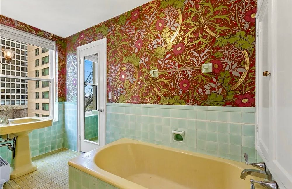 Real estate photo of a vintage bathroom with green tile and elaborate red wall paper located in a condo in Chicago’s Powhatan designed by Robert De Golyer and Charles L. Morgan in 1929.