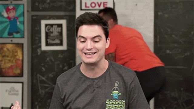 a man wearing a t-shirt with a toy story character on it is smiling in front of a sign that says love