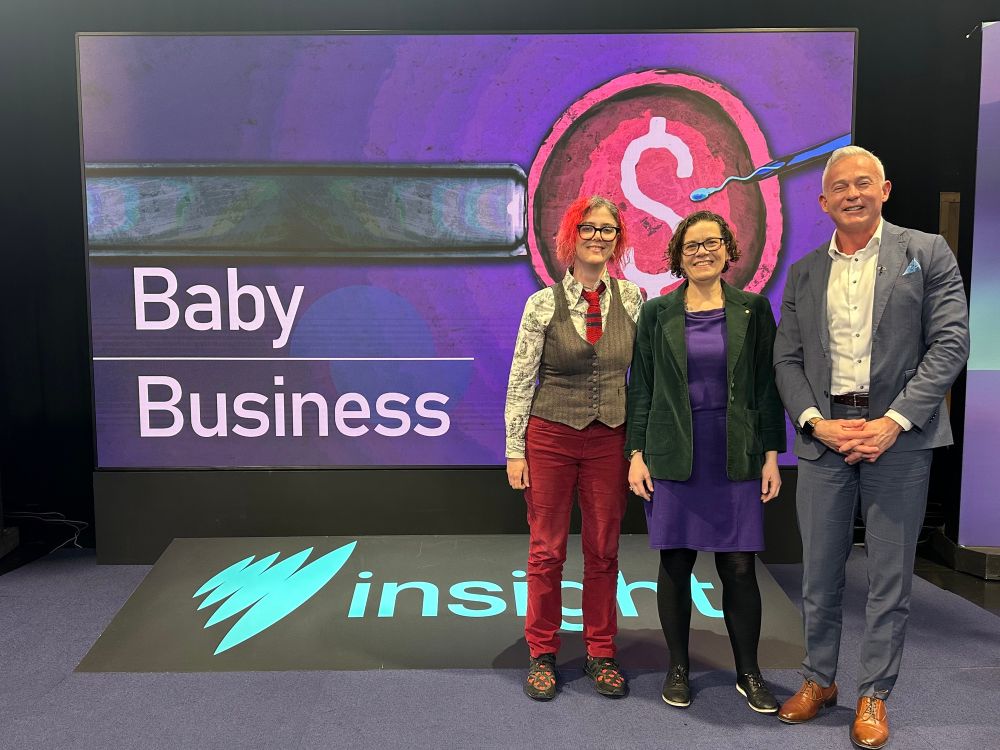 Three people standing in front of a sign that says Baby Business Insight.