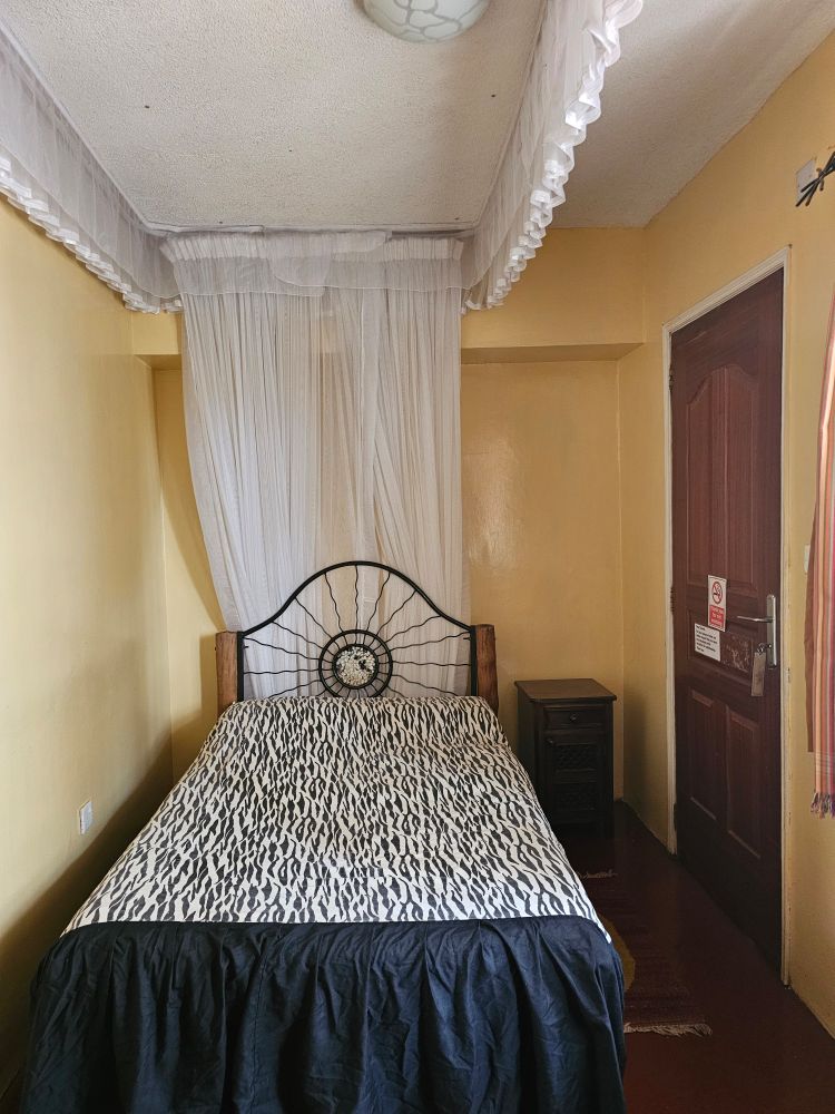 Ein kleines Hotelzimmer mit eknem Bett mit Zebra-Tagesdecke