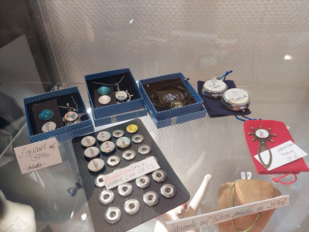 Weitere Schmuckstücke in einer Glasvitrine. Mehrere Druckknöpfe sowie Pillendosen