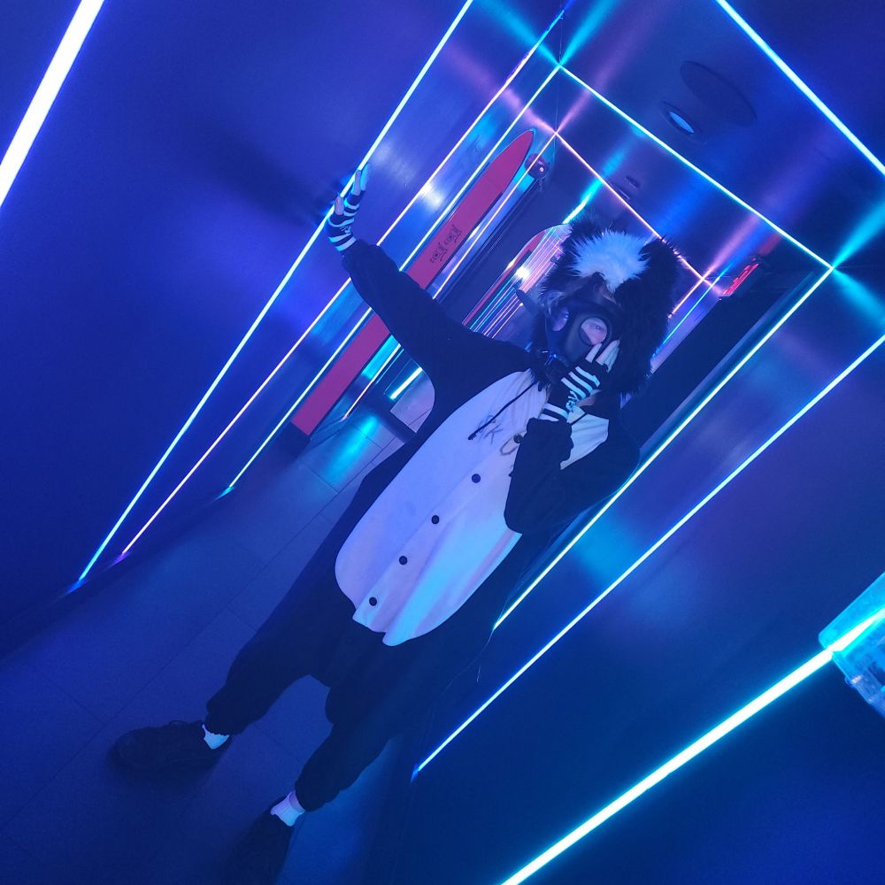 Skunk in a gas mask and kigurumi, standing in a hallway full of lights