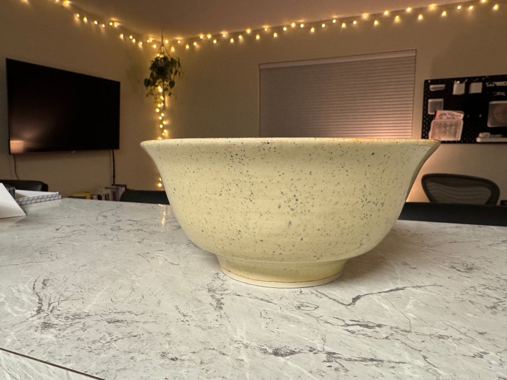 A stoneware ramen bowl glazed a tan color with rust undertones, and speckled with black underglaze