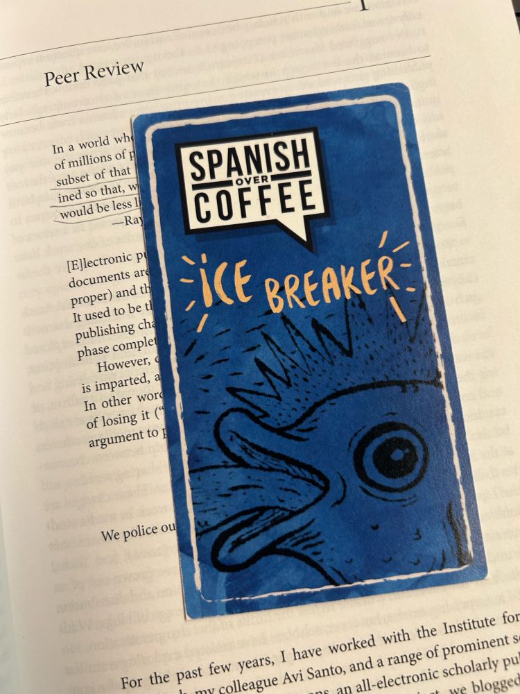 A blue rectangle bookmark reads Spanish over Coffee Ice Breaker. The image on the bookmark may be a fish spewing water from its mouth like a fountain. 