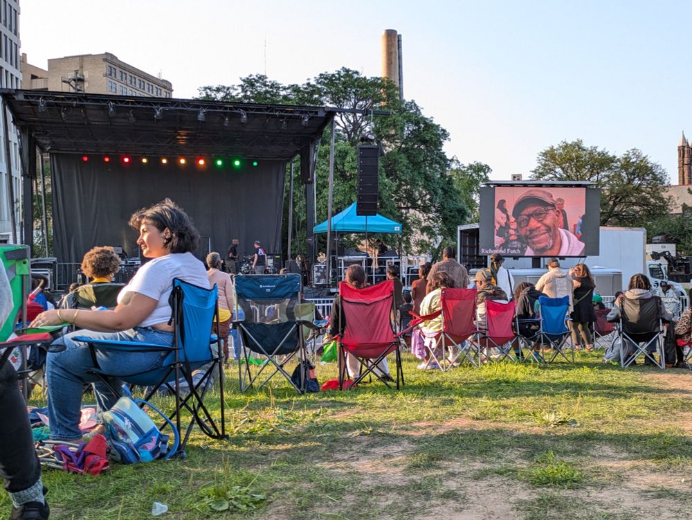 View of outdoor stage with musical equipment and a giant video screen with image of artist ancestor Richmond Dutch, Jr.