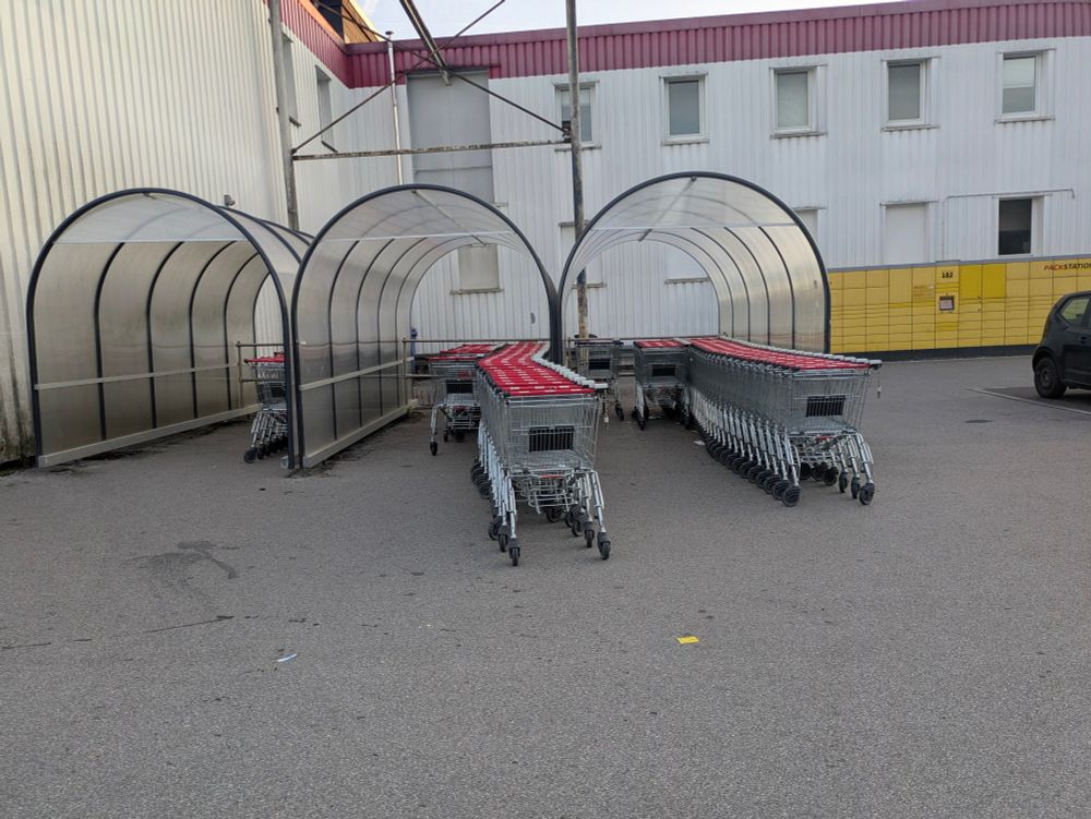 Eine Sammelstelle für Einkaufwagen. Hier können 3 mal 3 Reihen gebildet werden. In 3 Reihen steht gar kein Wagen und in 4 weiteren nur wenige. Zwei Reihen sind so voll, dass der Autoverkehr auf dem Parkplatz behindert wird.