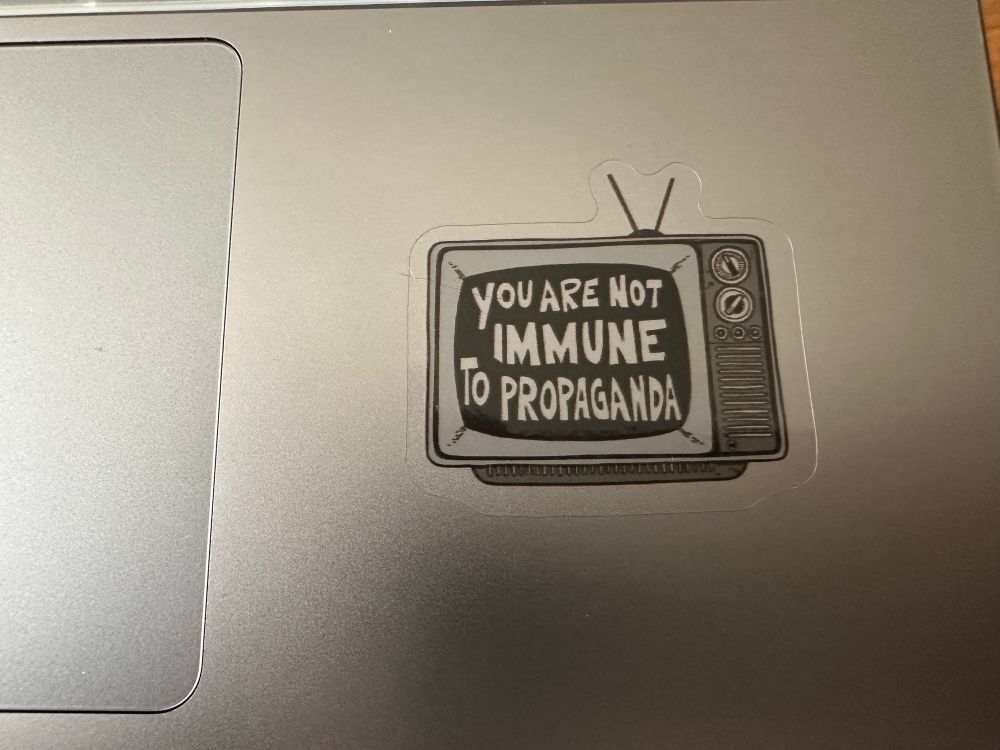 Sticker in the shape of an old box tv that says, “you are not immune to propaganda”