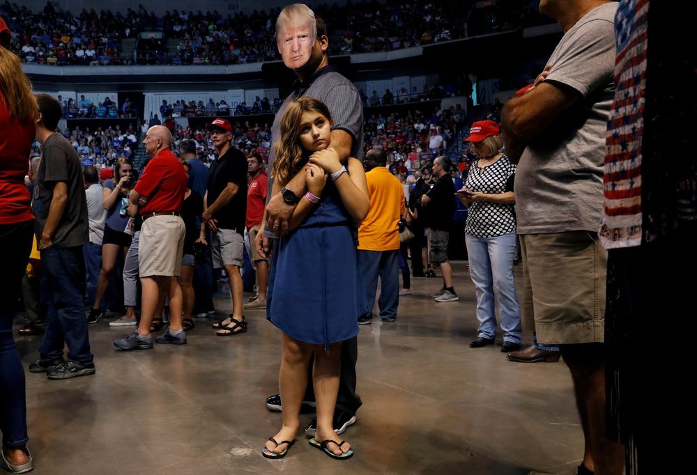 Thomas Musolino wears a mask of U.S. President Donald Trump while holding his daughter Gianna Musolino, 10, during a Trump campaign rally at Mohegan Sun Arena August 2, 2018 in Wilkes-Barre, Pennsylvania, U.S.
