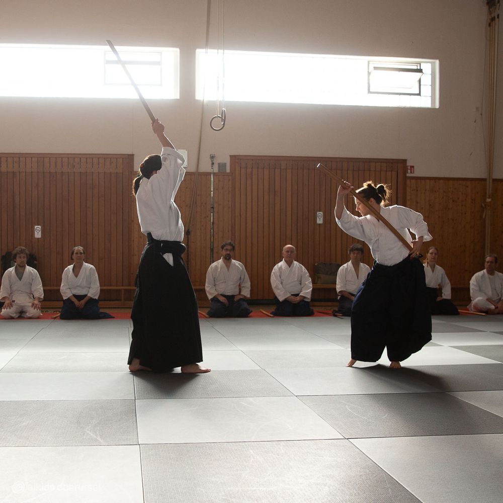 Female aikidoka showing a defense against an ambush attack with wooden swords