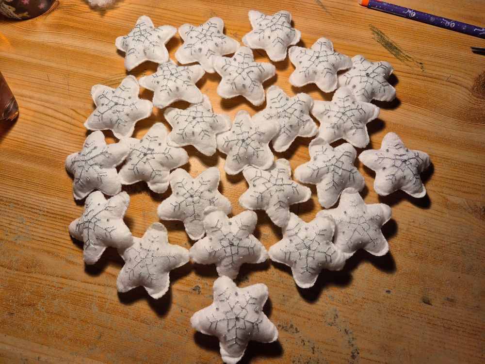 24 weiße gefüllte Filzsterne mit silberner Schneeflockenstickerei.
