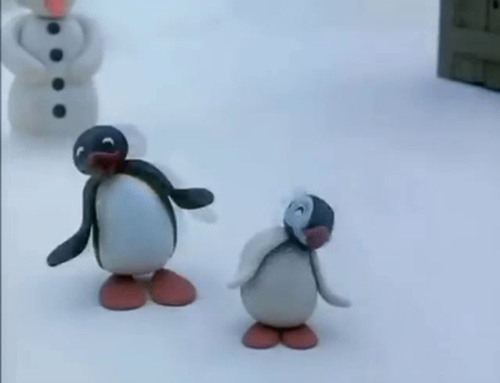 two penguins are standing in the snow in front of a snowman .