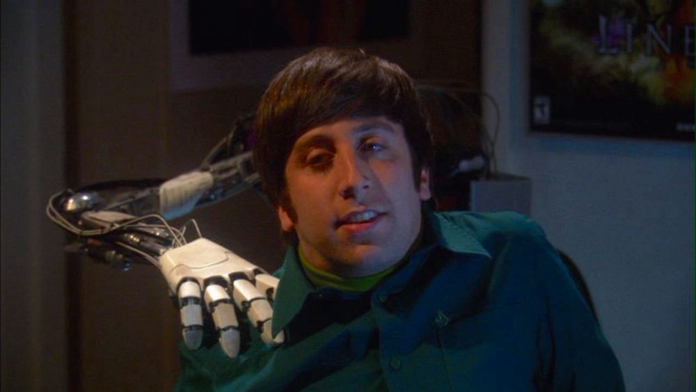 Howard Wolowitz with a robotic hand massaging his shoulder has a look on his face indicating a he has an idea; an awful terrible idea