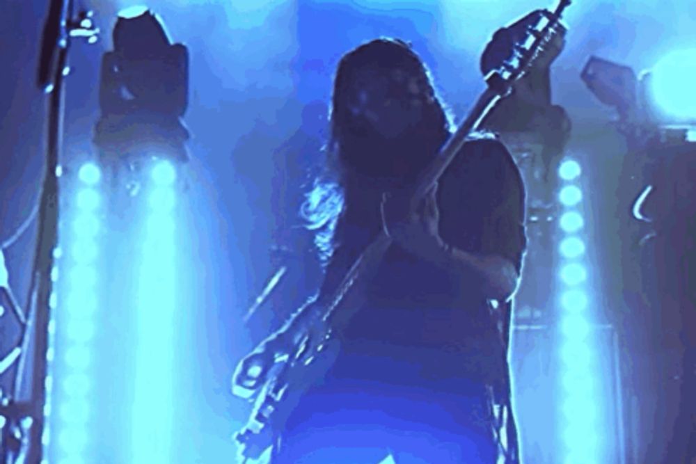 a man with long hair is playing a guitar in a dark room