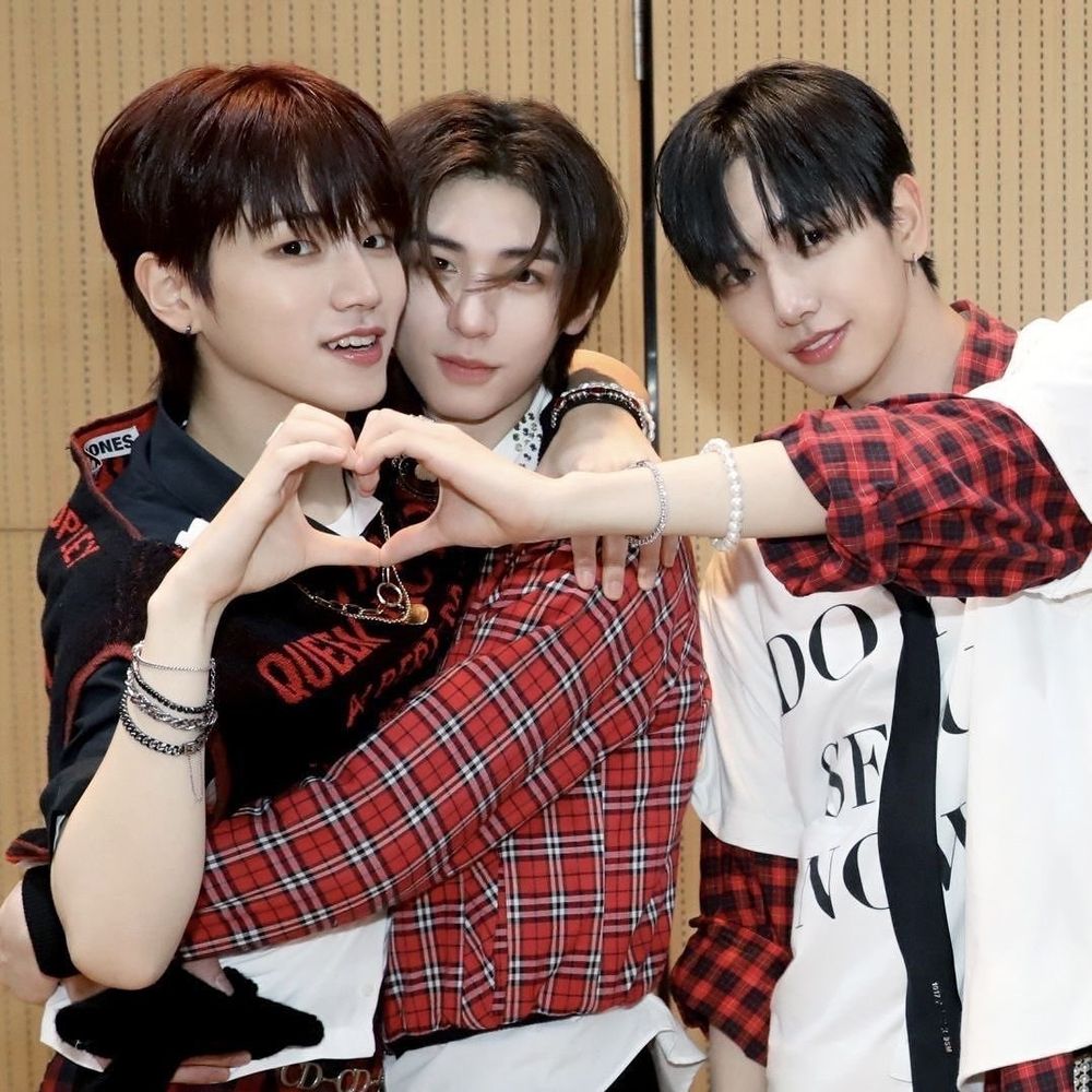 Riwoo, Leehan, and Myung Jaehyun of BoyNextDoor.
Leehan is hugging Riwoo, who has his arm around Leehan. Riwoo and Jaehyun have their hands together, making a heart.