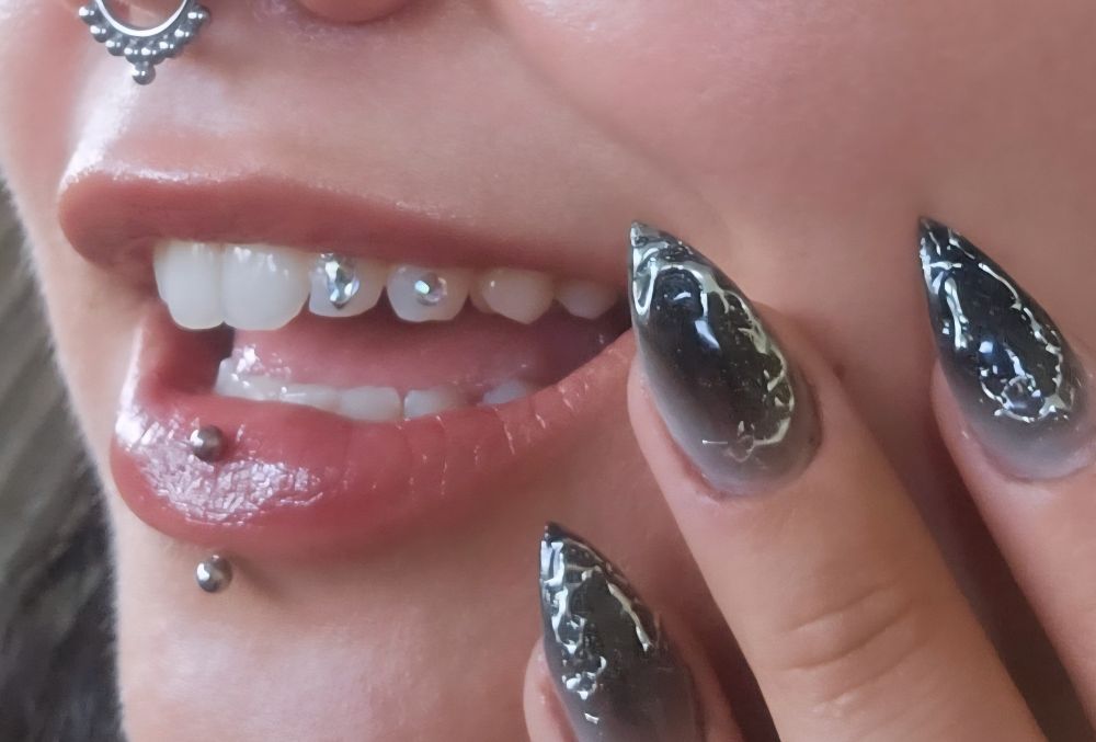 skoom has two lil teeth gems and chrome tipped black nails, and a nose ring, and a vert labret . yay! 