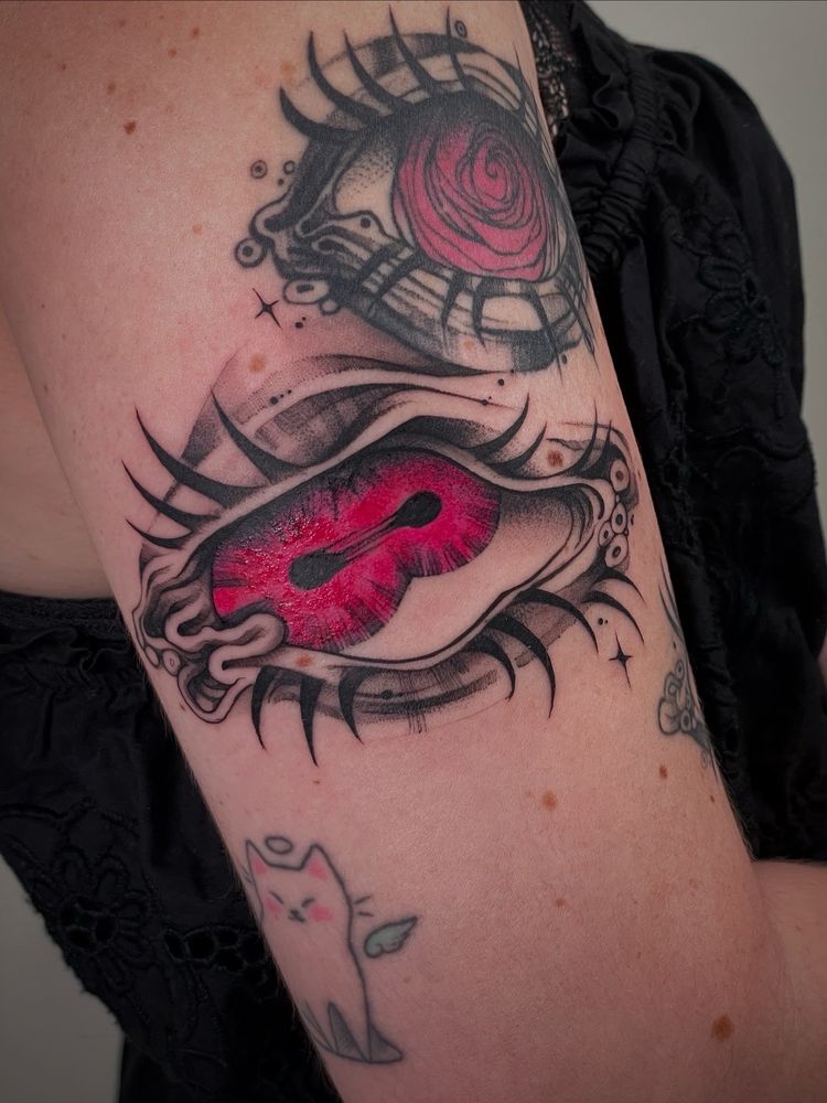 Sentinel eye blackwork tattoo with pink iris on upper arm