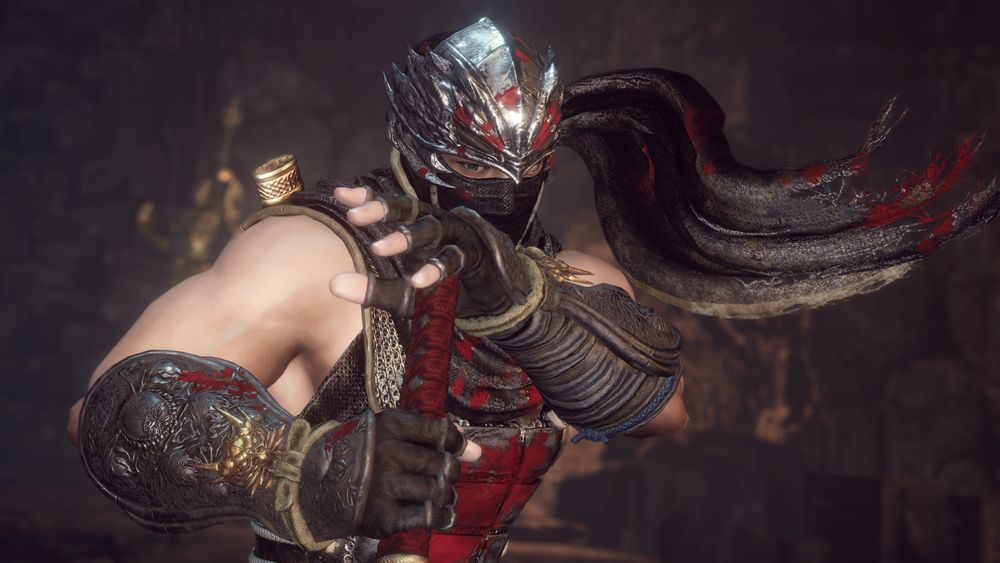 Screenshot of Ren Hayabusa taken in Nioh 2's photo mode. Ren is grasping the Dragon Sword and pressing his left palm against the end of the handle as he stabs downwards. His scarf is blowing in the air to the right of him. The background is out of focus, and Ren is covered in blood.