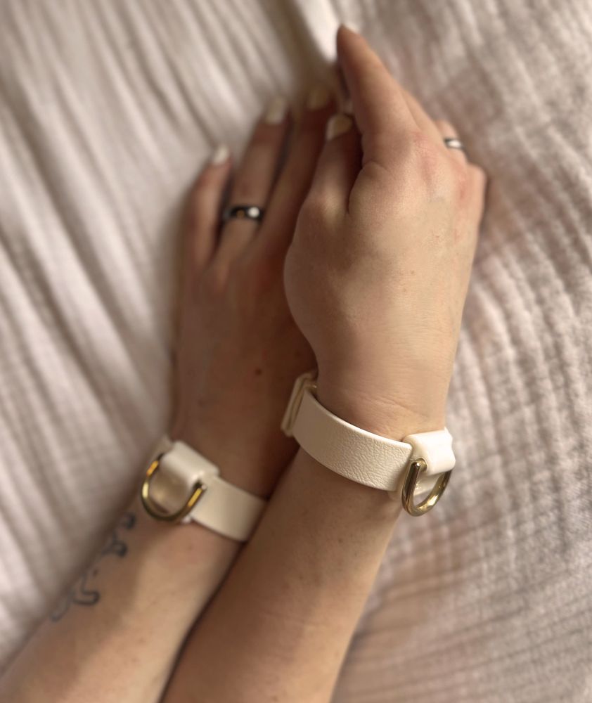 A picture of me wearing a set of two white Biothane cuffs with a brass D-ring made by @beltbolt.co.uk‬