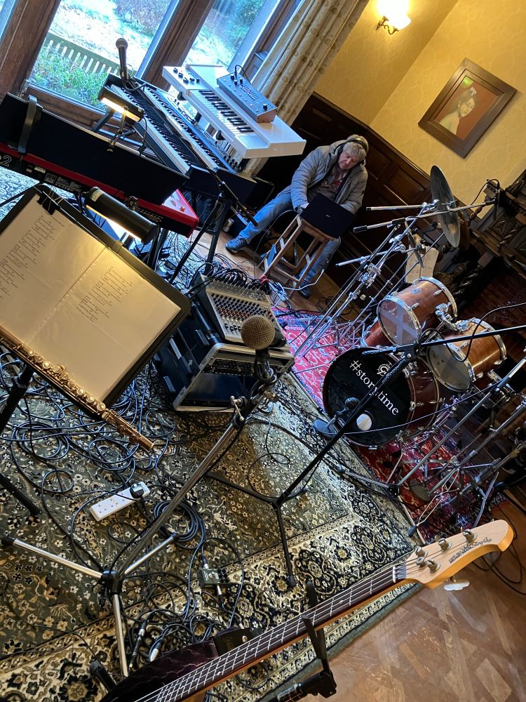 A tangle of musical instruments; cables; drums and equipment, over a series of colourful rugs.