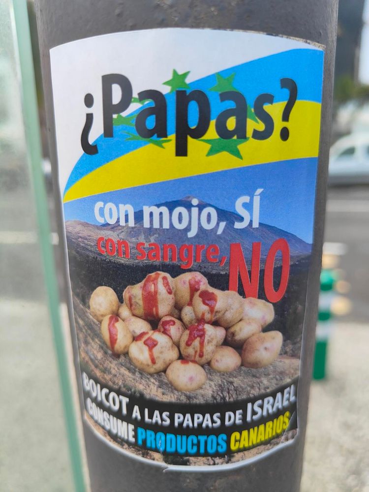 Foto de una pegatina puesta en una farola, que sobre la bandera canaria y unas papas con rojo por encima dice: "¿Papas? Con mojo, SÍ. Con sangre, NO. Boicot a las papas de Israel. Consume productos canarios"