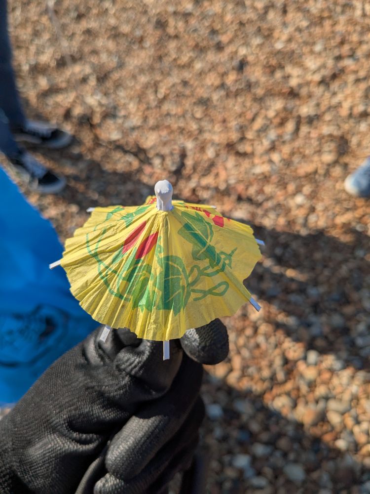 Little cocktail umbrella held up by a gloved hand 